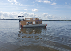 A fotografia mostra um barco no rio Tocantins. Ele está centralizado na imagem e de lado para o observador, indo à direita. Ao fundo, o céu está claro.